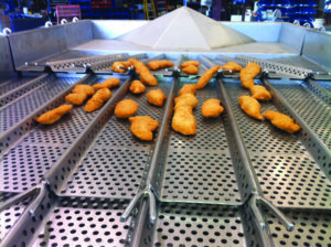 A vibratory food conveyor system made of stainless steel trays keeps chicken tenders sanitary. 