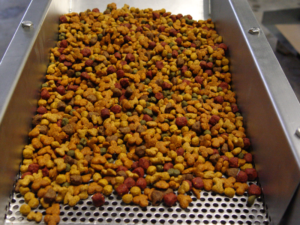 During pet food processing, the product passes through a vibratory feeder.