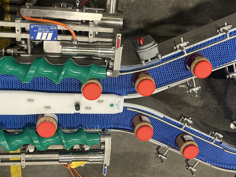 Jars of peanut butter moving on an automated conveyor system.